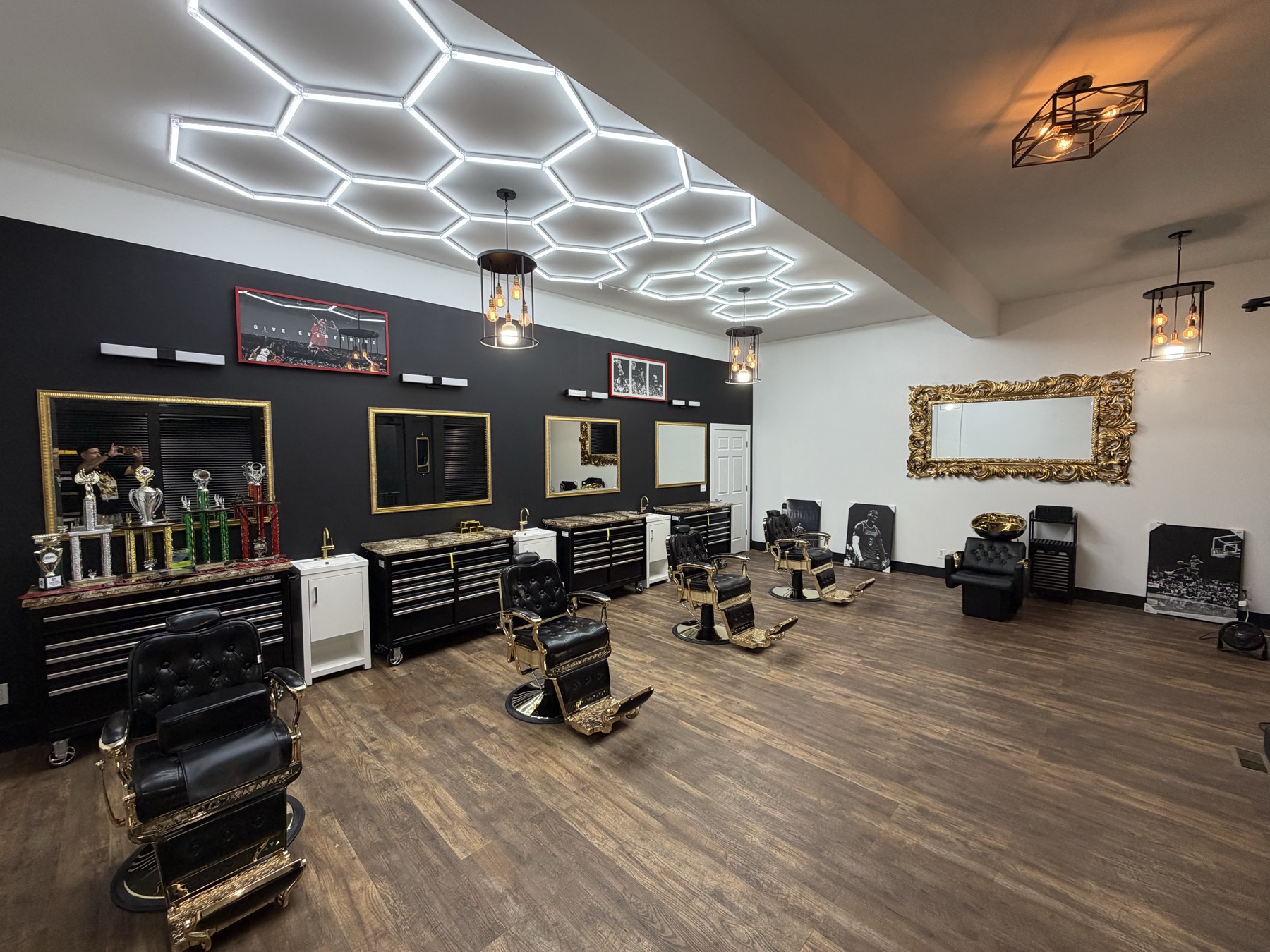 Interior de X Express Barbershop Studio — sillas de barbero con detalles dorados bajo luces LED hexagonales