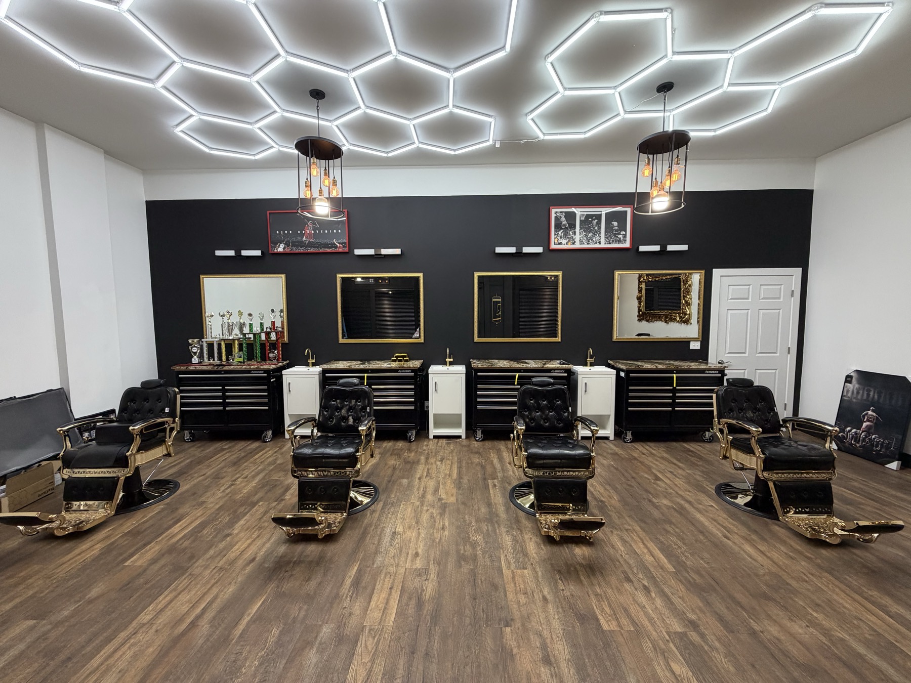 Interior de X Express Barbershop Studio — sillas de barbero, espejos dorados y piso de madera oscura